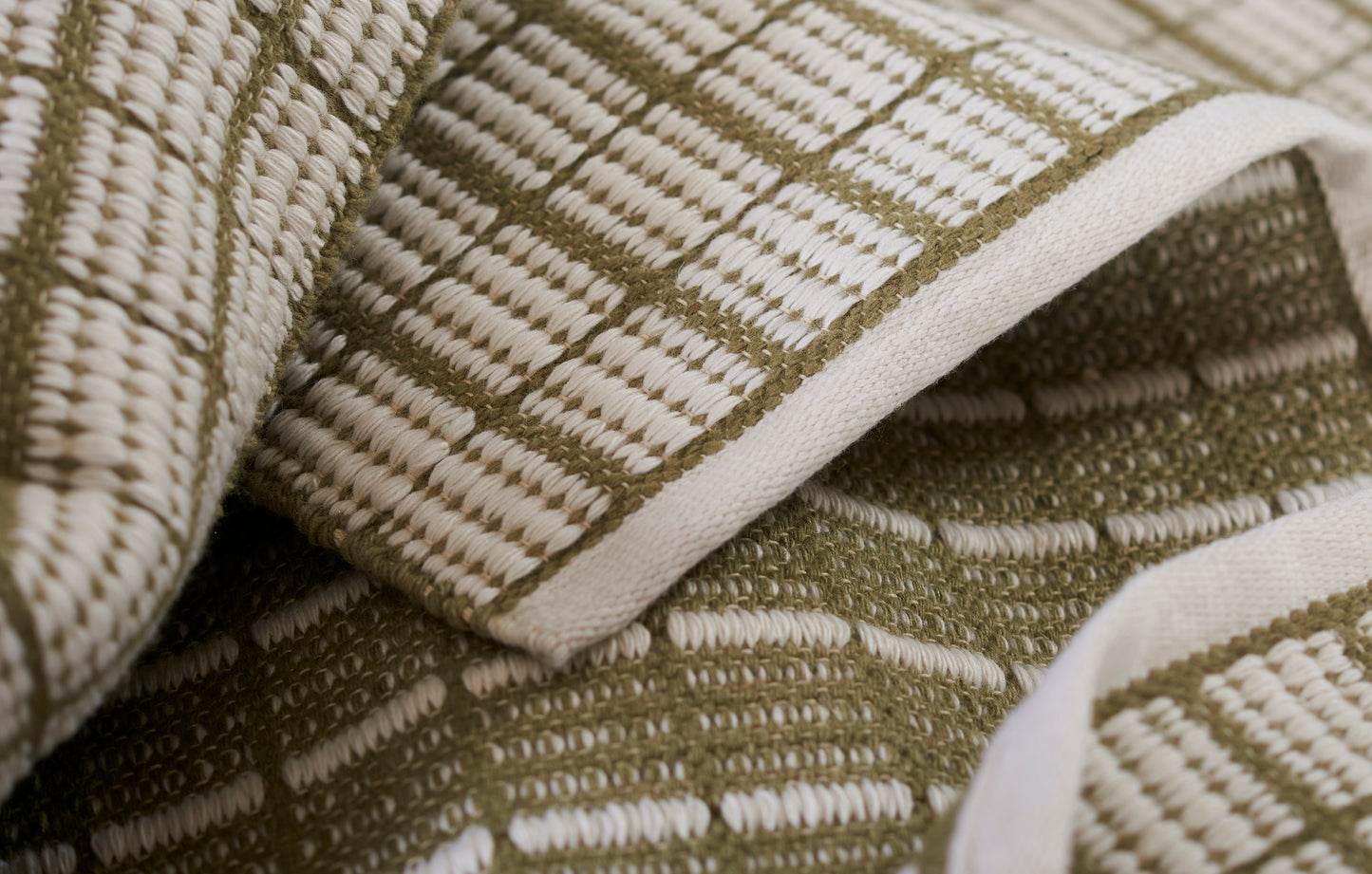 Beige and olive checkered woven throw with a grid pattern and thick textured fabric.