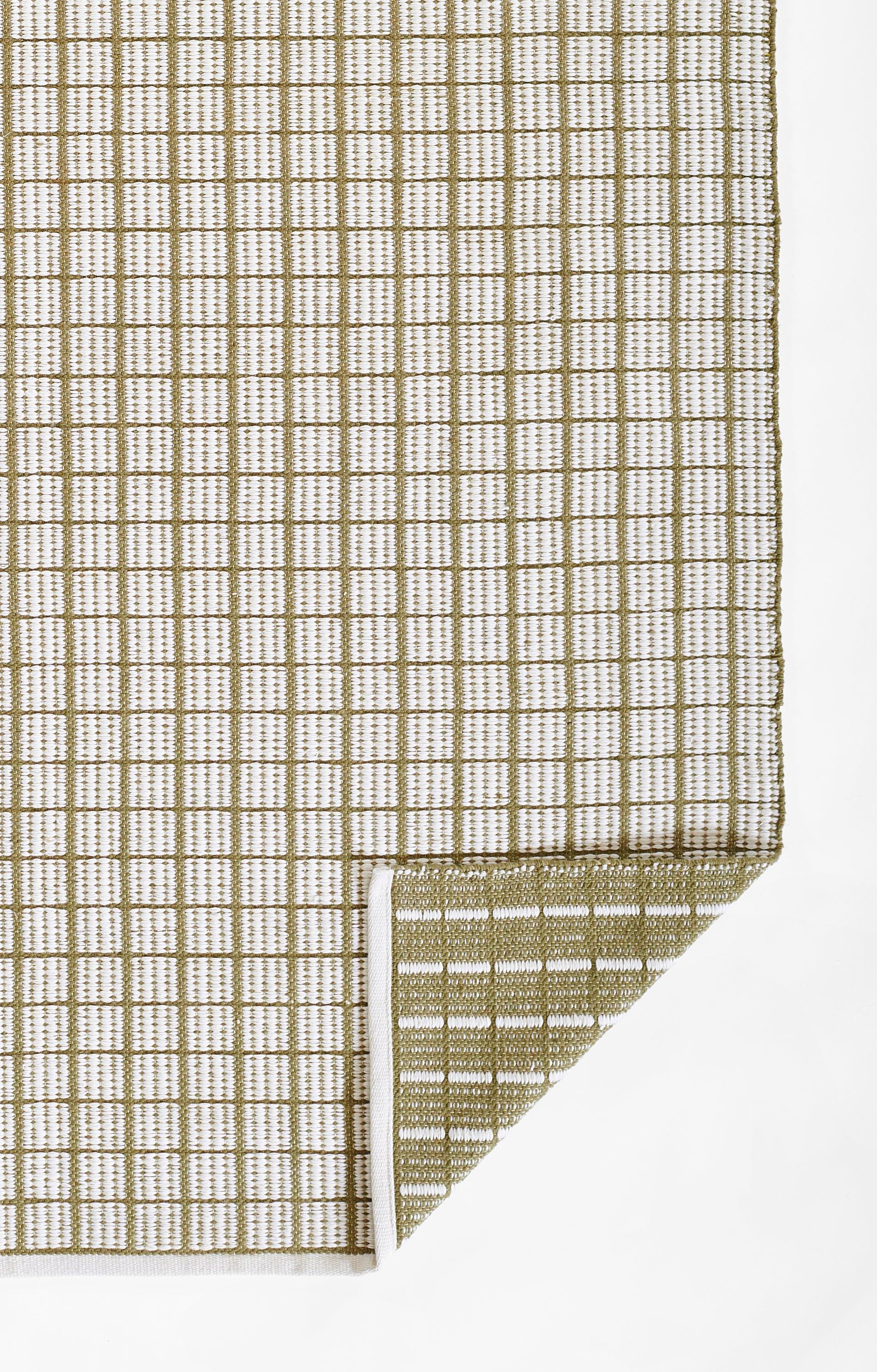 Beige woven area rug with brown grid pattern, rectangular shape, folded corner.