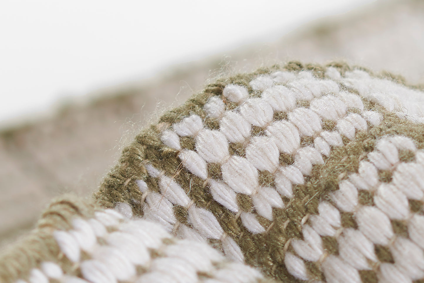 Olive green and ivory boucle knit blanket with chunky textured stitches, cozy home decor.