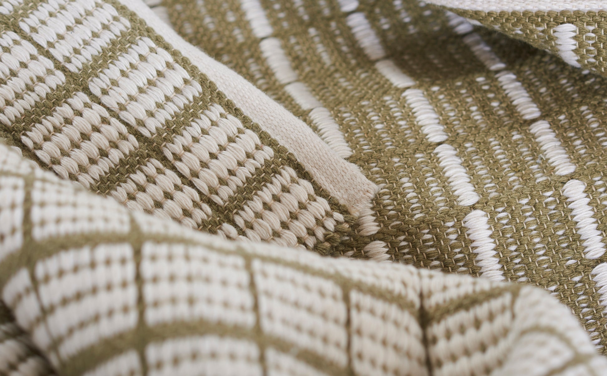 Close-up of beige and olive woven textile with geometric grid pattern, rustic rug or throw.