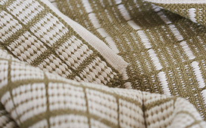 Close-up of beige and olive woven textile with geometric grid pattern, rustic rug or throw.