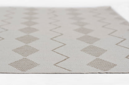 Neutral woven rug with beige diamonds and zigzag lines on a light gray background.