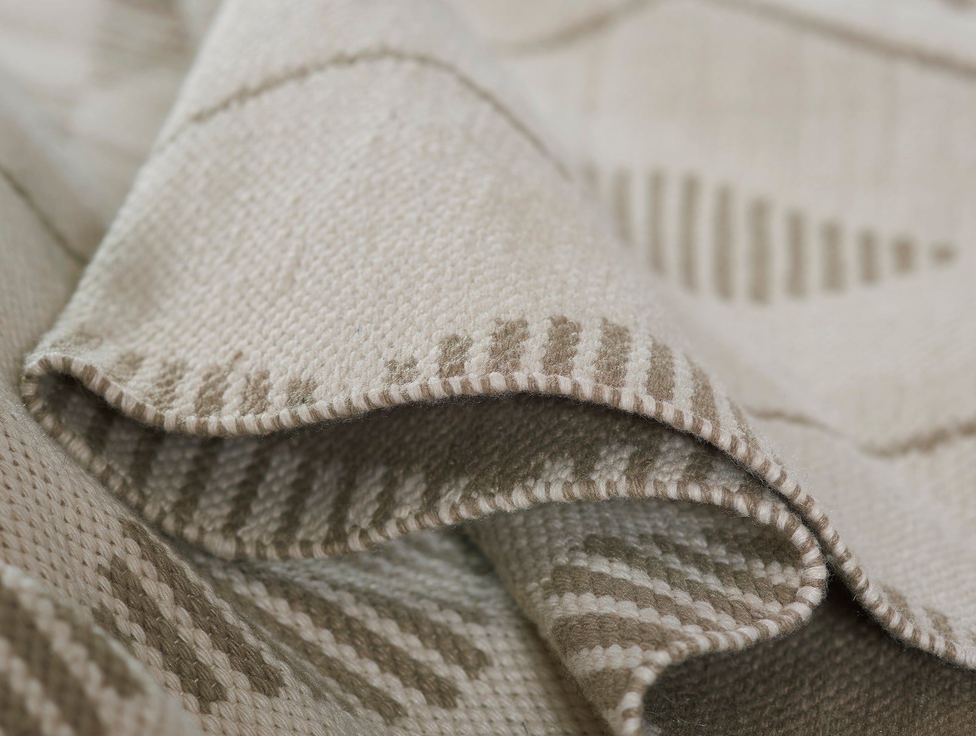Beige woven rug with tan striped pattern and natural fiber texture.