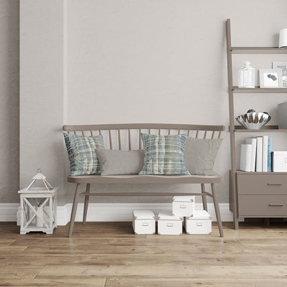 Taupe wooden bench with slat back and four cushions (two striped teal, two solid gray) in a living room with shelving.