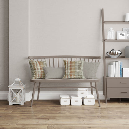 Taupe wooden spindle-back bench with plaid and gray cushions, in a neutral living room with shelving and white storage boxes.