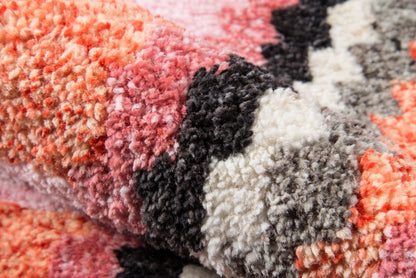 Close-up of a multicolor shag rug: pinks, peaches, grays, black and ivory color blocks, soft high-pile plush.