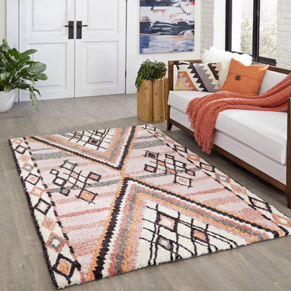 Shaggy geometric rug in pink, peach, cream and black with a tribal pattern, on a wood floor beside a white sofa.