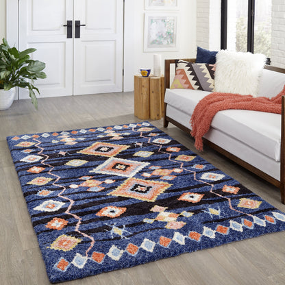 Rectangular navy blue shag rug with multicolor geometric diamond pattern in orange, cream and yellow, in a living room.