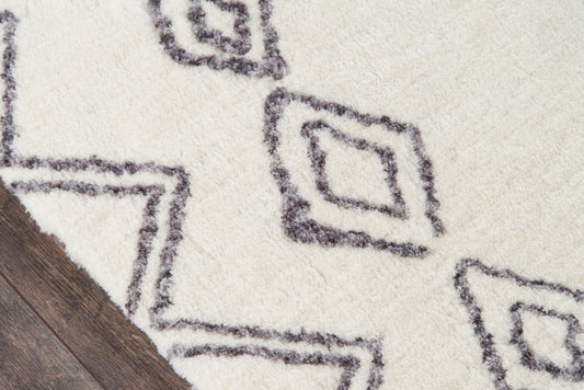 Cream shag rug with charcoal geometric diamond motifs on dark wood floor, plush pile