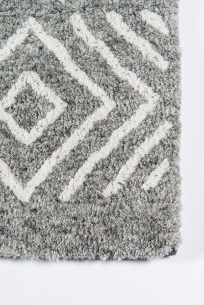 Grey shag rug with white diamond chevron pattern, plush thick pile, close-up of corner edge.