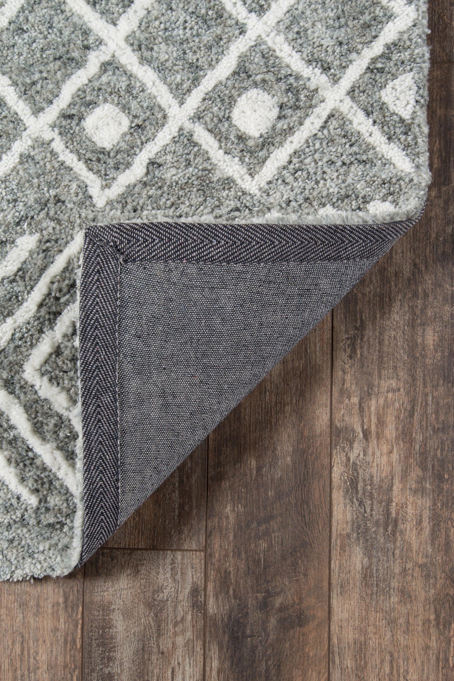 Grey shag rug with white geometric diamond lattice; folded corner reveals navy denim-like reverse.