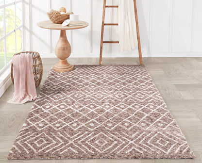 Beige-brown geometric shag rug with diamond pattern on light wood floor, beside wicker basket, round wooden table & ladder.