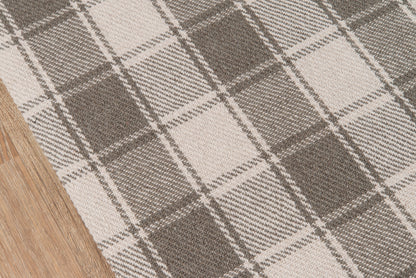 Beige and gray plaid rug with chunky woven texture on wooden floor.