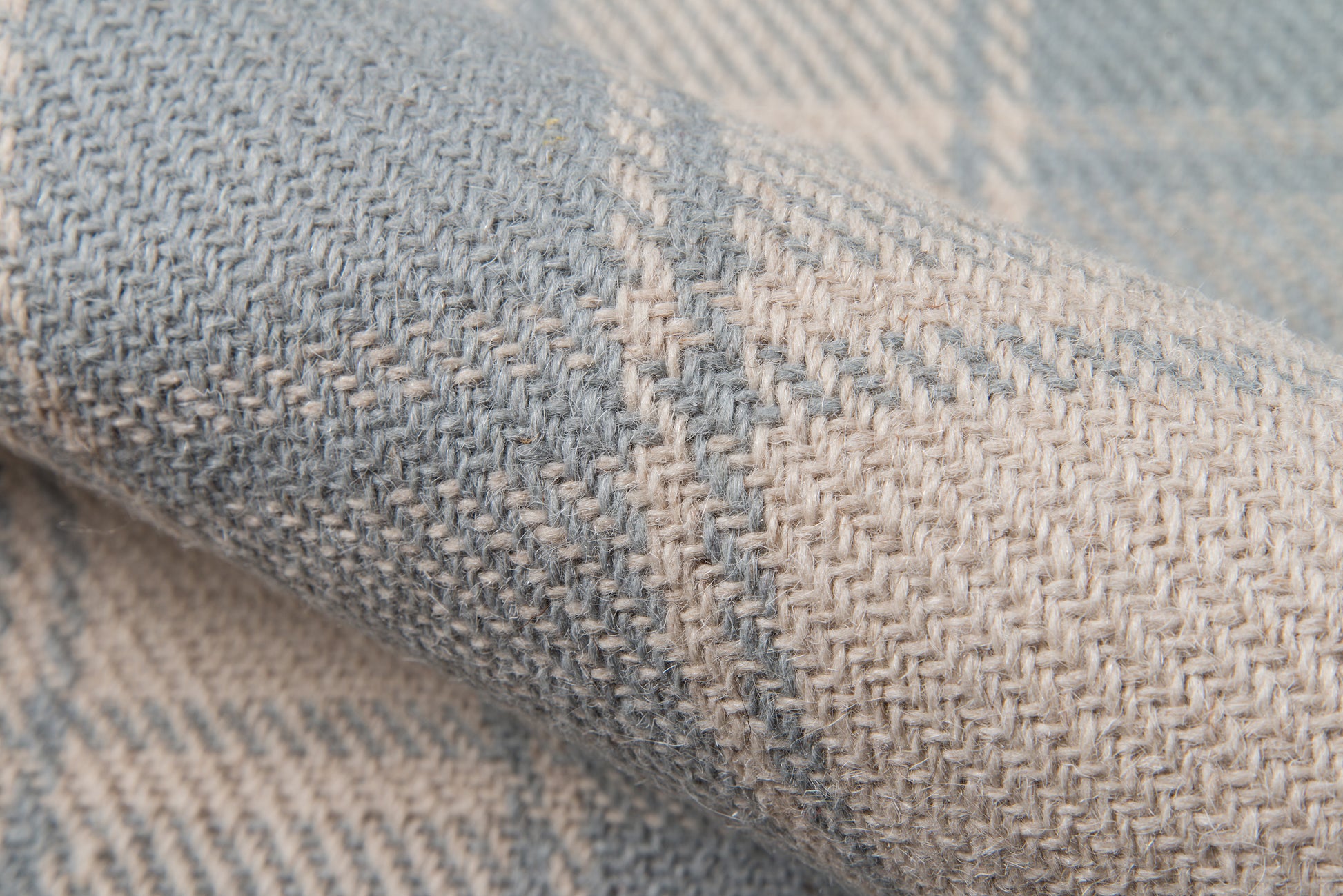 Close-up of blue and cream woven rug with a textured herringbone pattern and gentle fold.