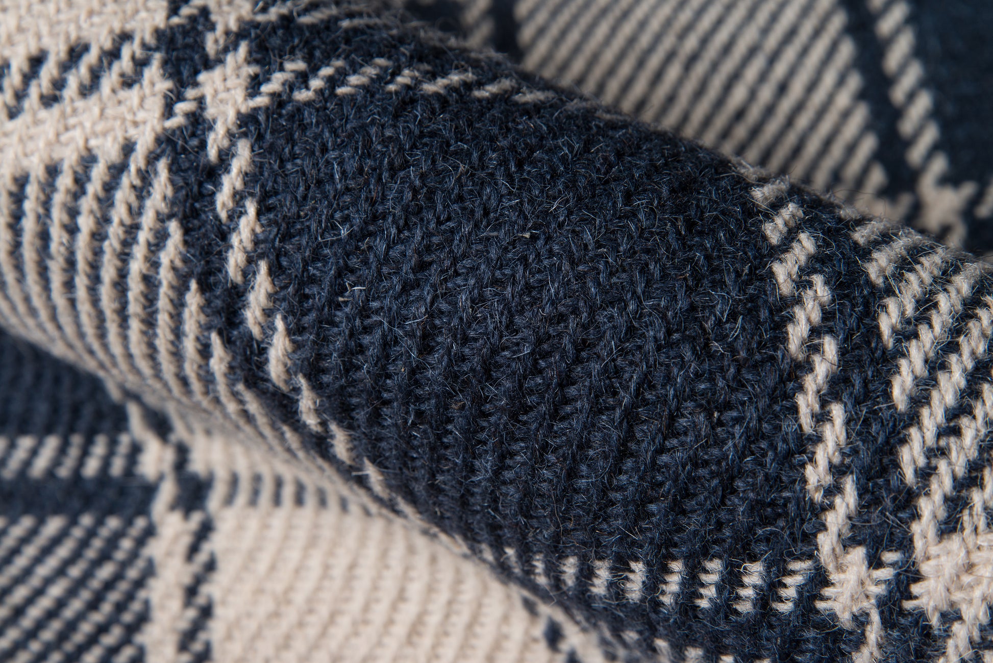 Close-up of navy and cream plaid knit fabric with thick yarn, cozy scarf or throw.