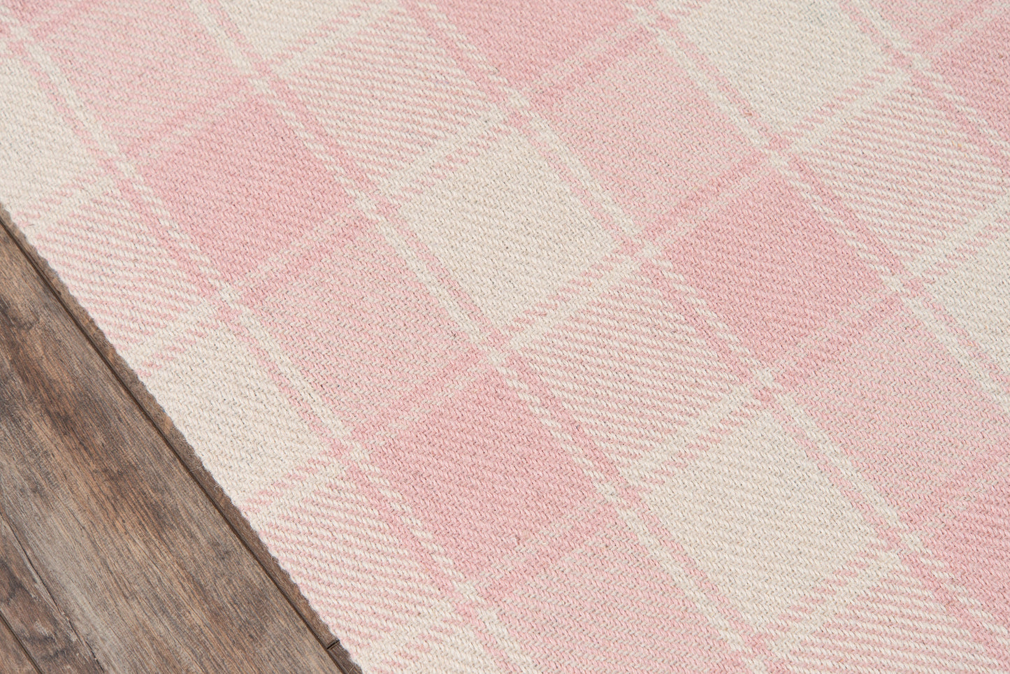 Pink and cream plaid woven rug with soft texture on wood floor; ideal for living room or bedroom.