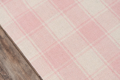 Pink and cream plaid area rug on wooden floor.