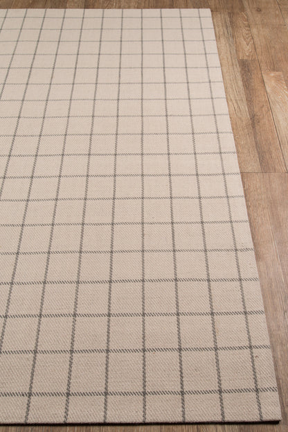 Beige woven rug with dark gray grid pattern on wooden floor.
