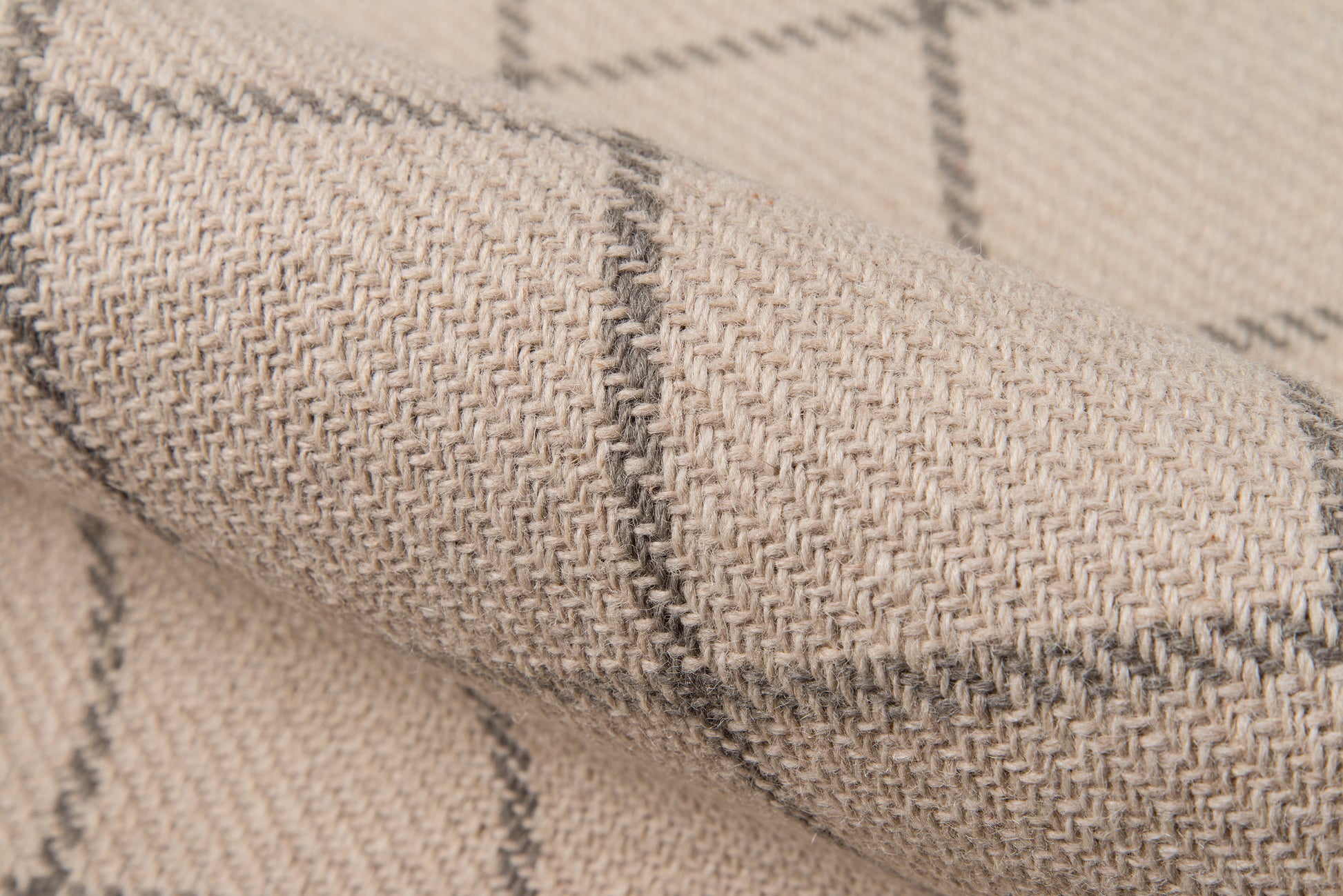 Beige plaid woven rug close-up; textured weave with gray grid lines.