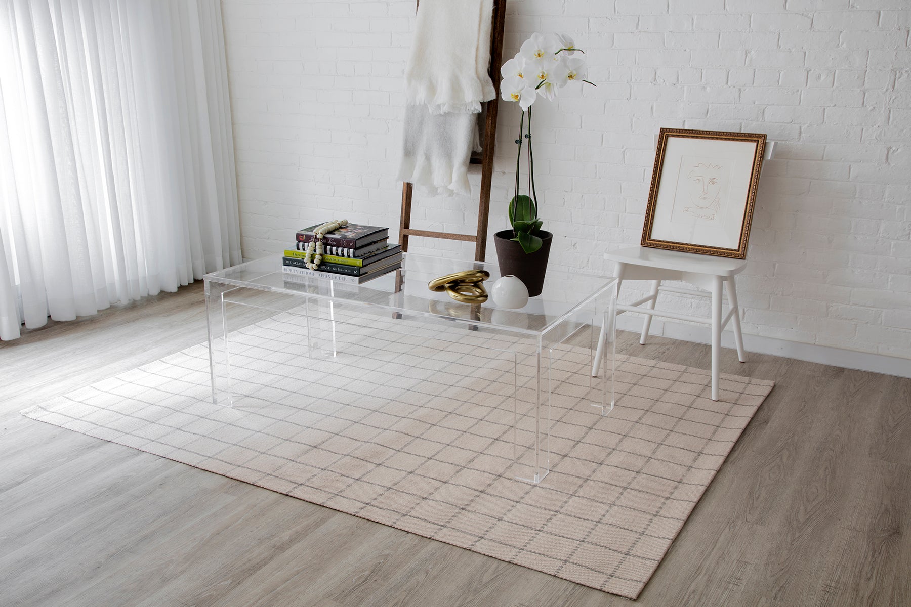 Beige grid runner rug (2'3" x 8') in a bright white room with a clear acrylic rectangular coffee table, books, an orchid plant, and a framed artwork.