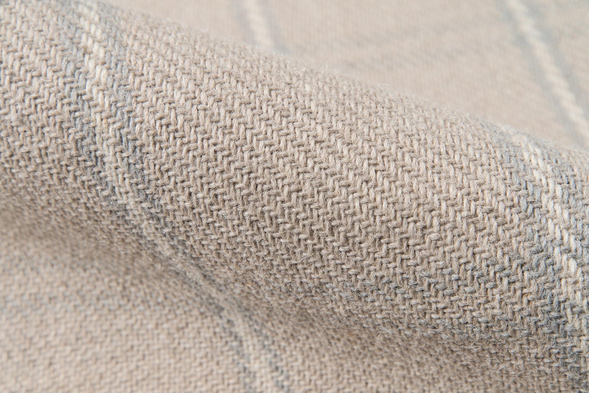 Beige-gray woven fabric close-up with tight herringbone texture, folded to show soft upholstery-style textile.