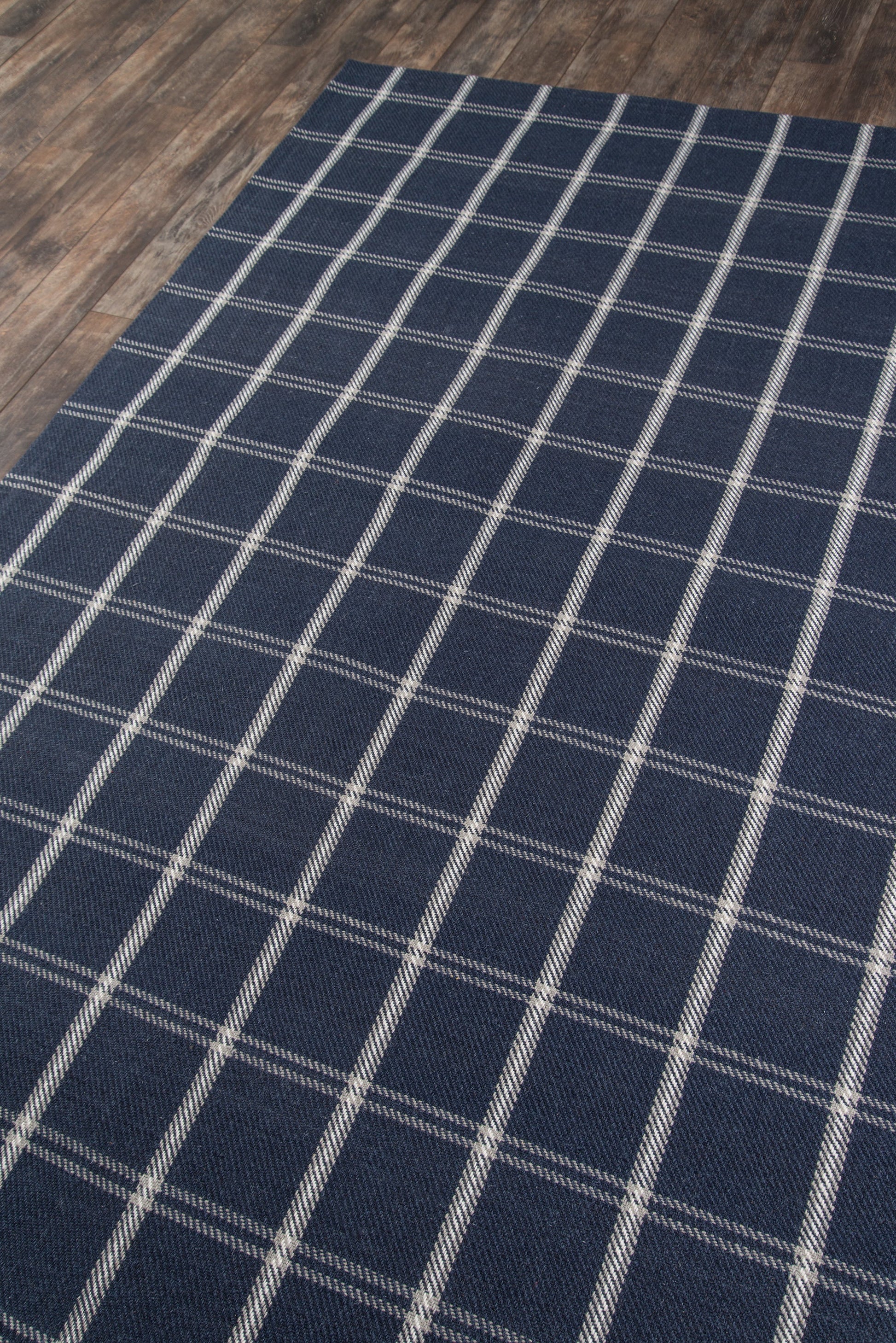 Navy blue runner with a white plaid grid pattern on a wood floor.