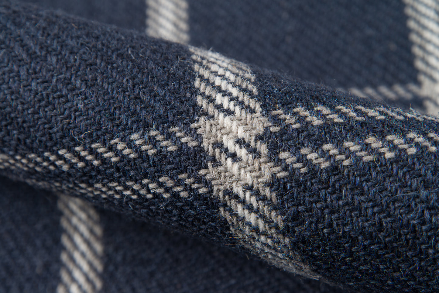 Close-up of navy marl woven rug with light gray plaid stripes; soft, chunky pile.