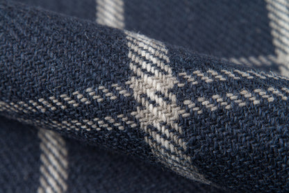 Close-up of navy marl woven rug with light gray plaid stripes; soft, chunky pile.