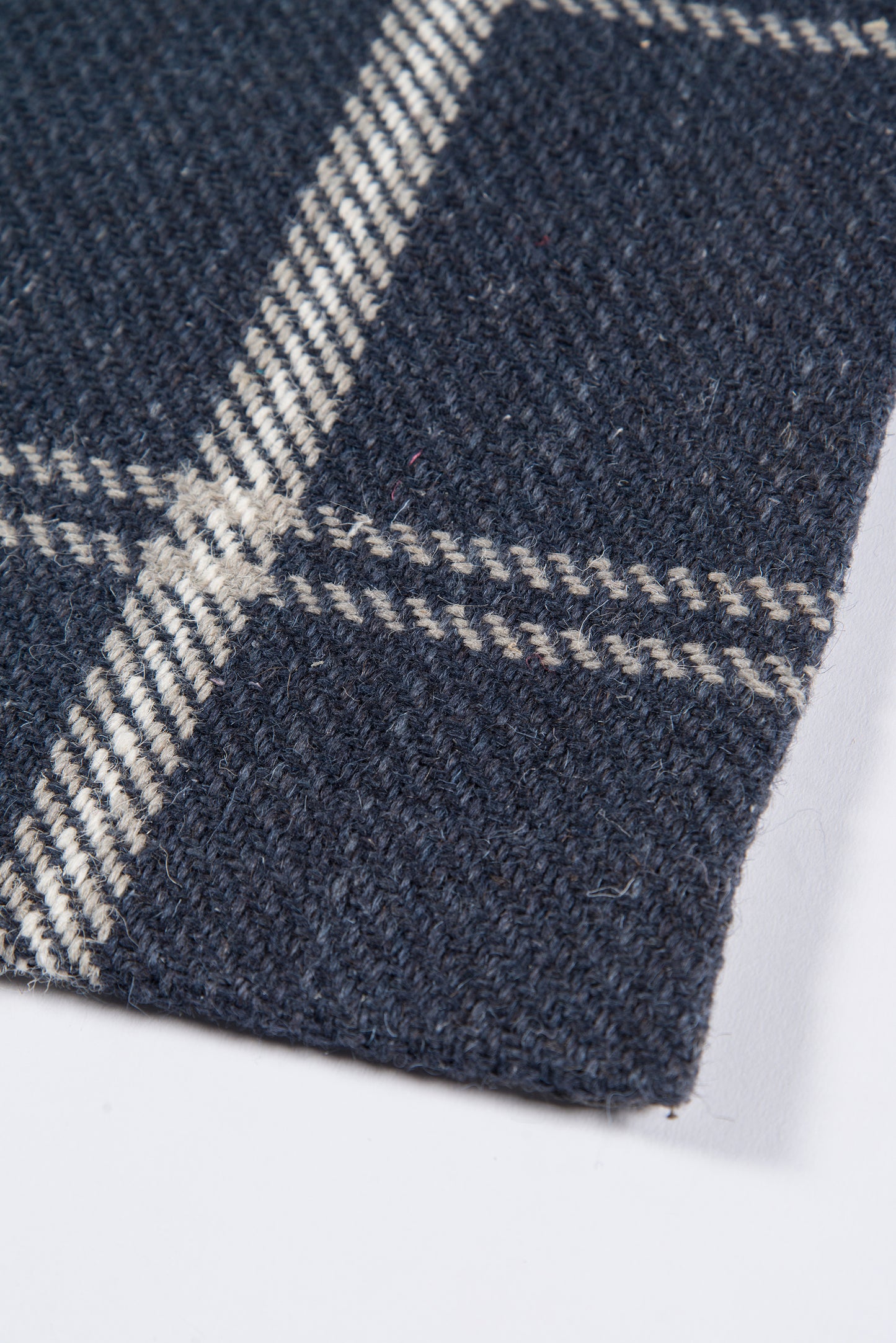 Navy plaid rug with white stripes; textured woven rug material.