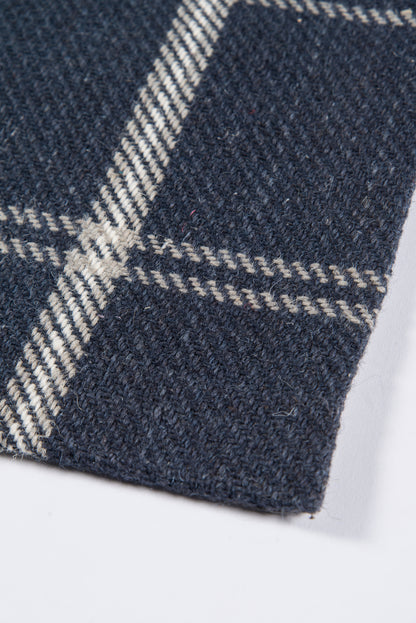 Dark navy wool plaid rug with white stripes; close-up woven texture, rectangular rug.