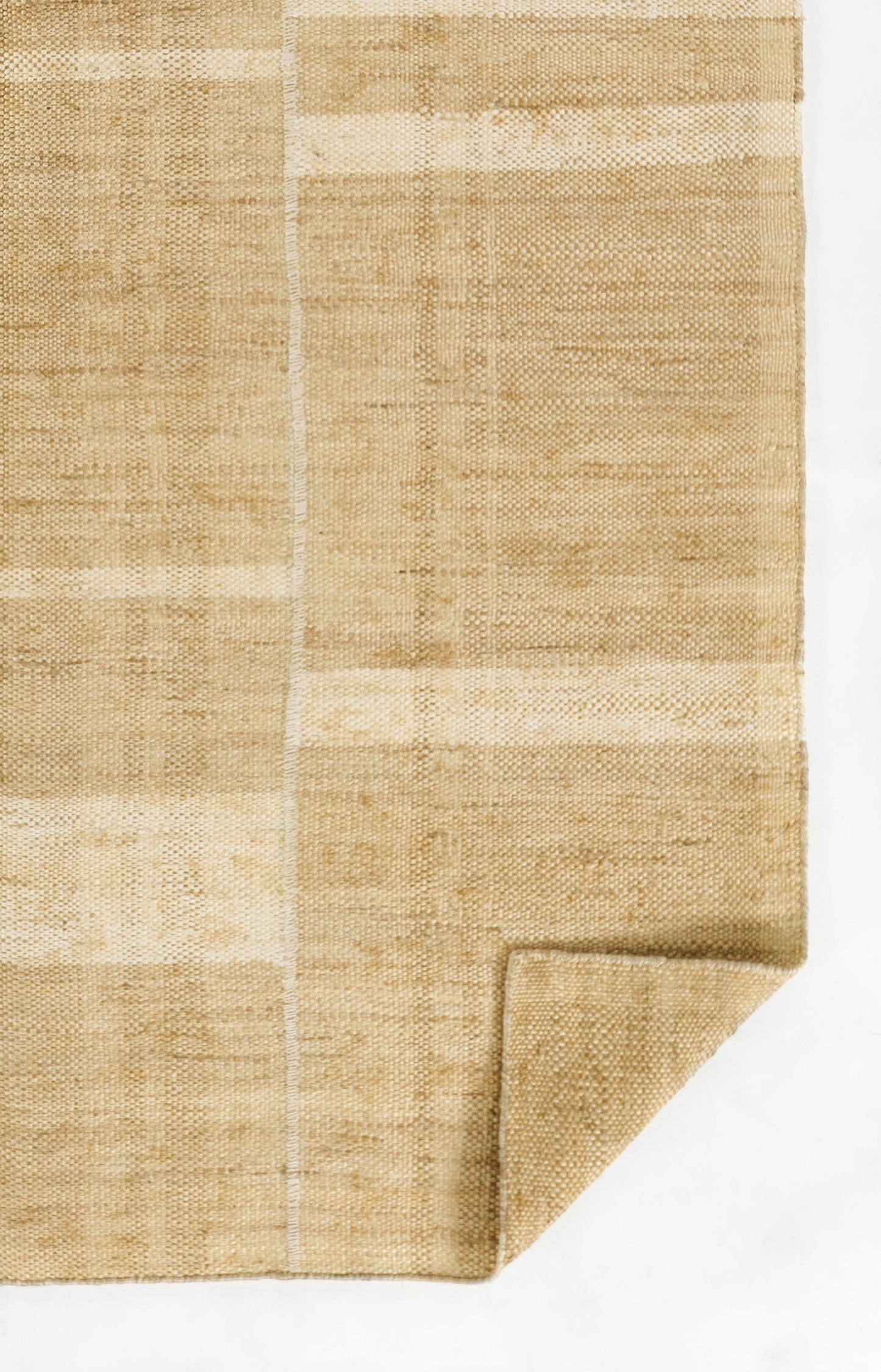 Natural beige woven rug with subtle patchwork blocks, rough jute-like texture, folded corner.