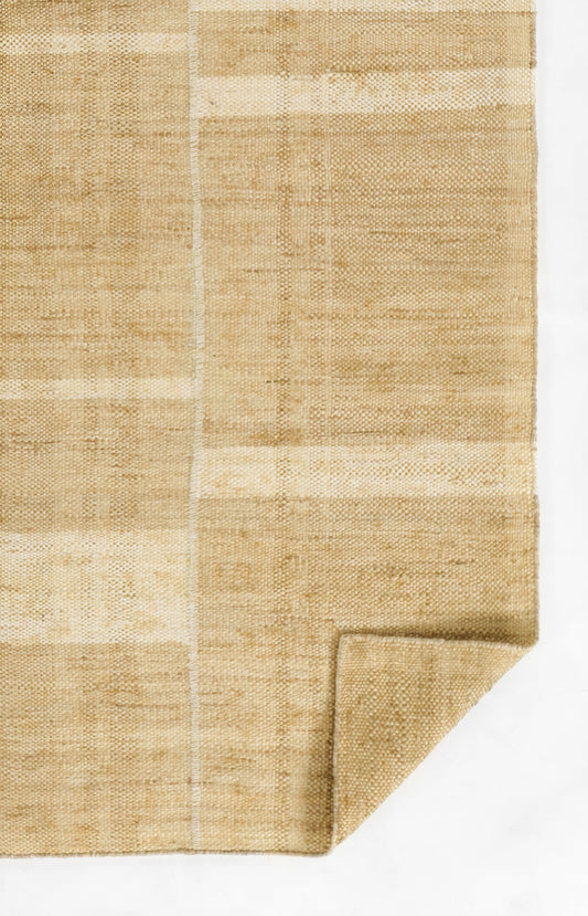Beige natural fiber rug with warm tan tones, woven texture & subtle rectangular patchwork, folded corner.