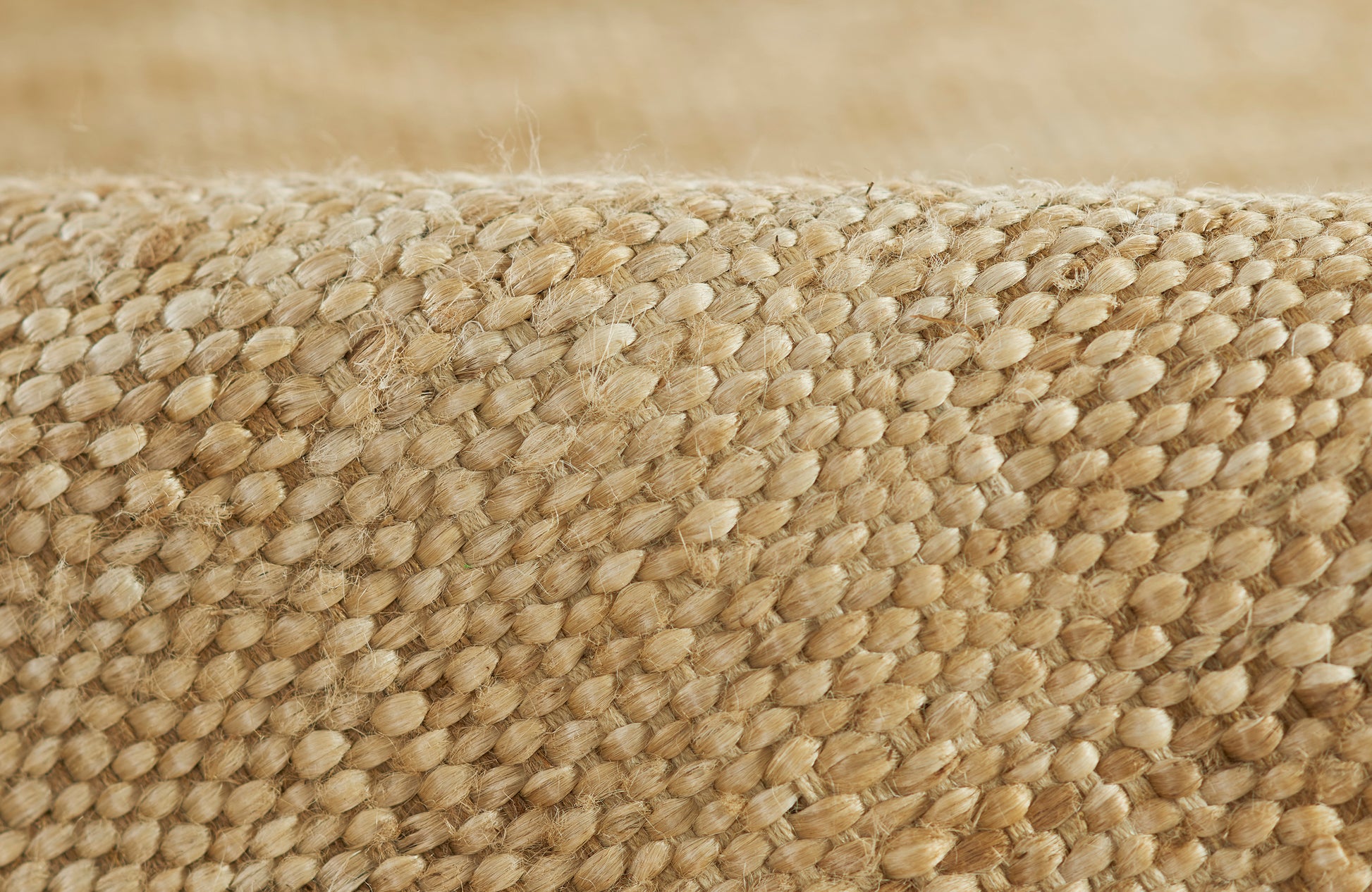 Close-up of natural jute woven rug with beige fibers and textured loop pattern.