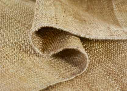 Natural beige burlap-style rug close-up with folded edges, coarse woven jute texture.
