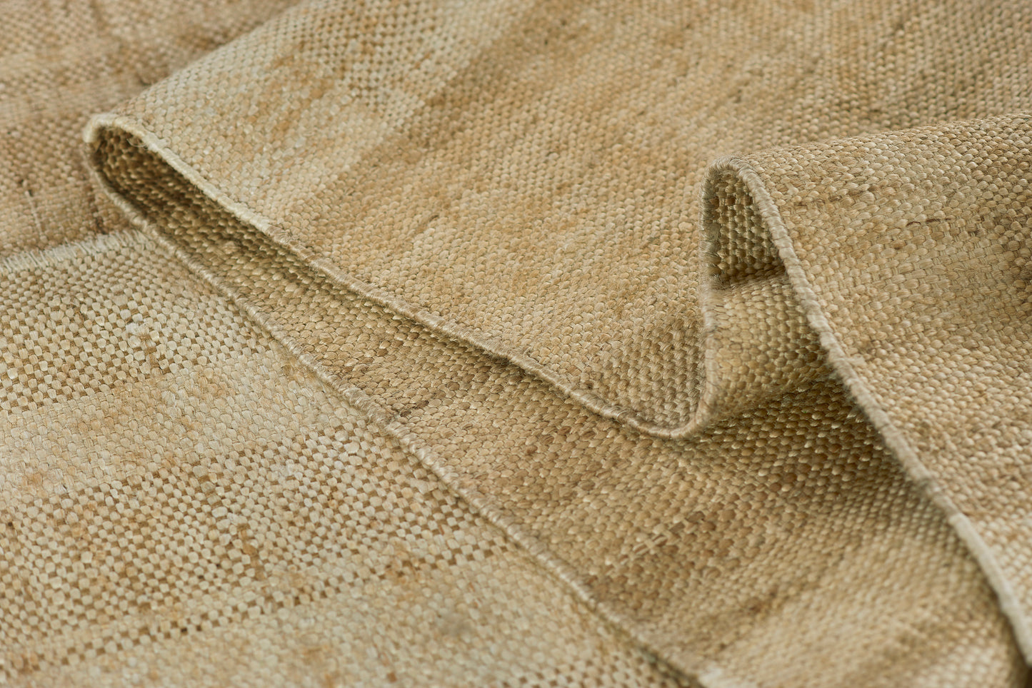 Beige natural-fiber woven rug with tight checker weave and rolled edge.