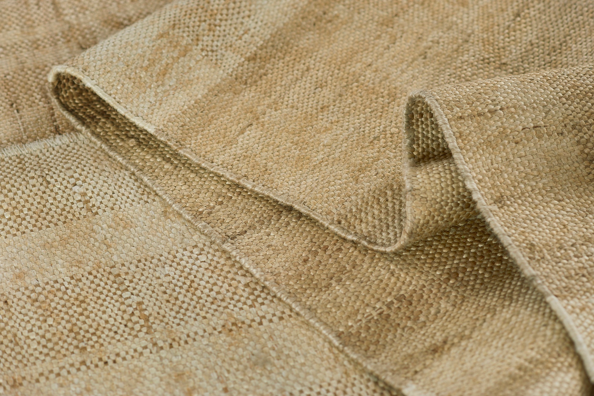 Beige natural jute rug with tight woven texture & rolled edge, rustic home decor.