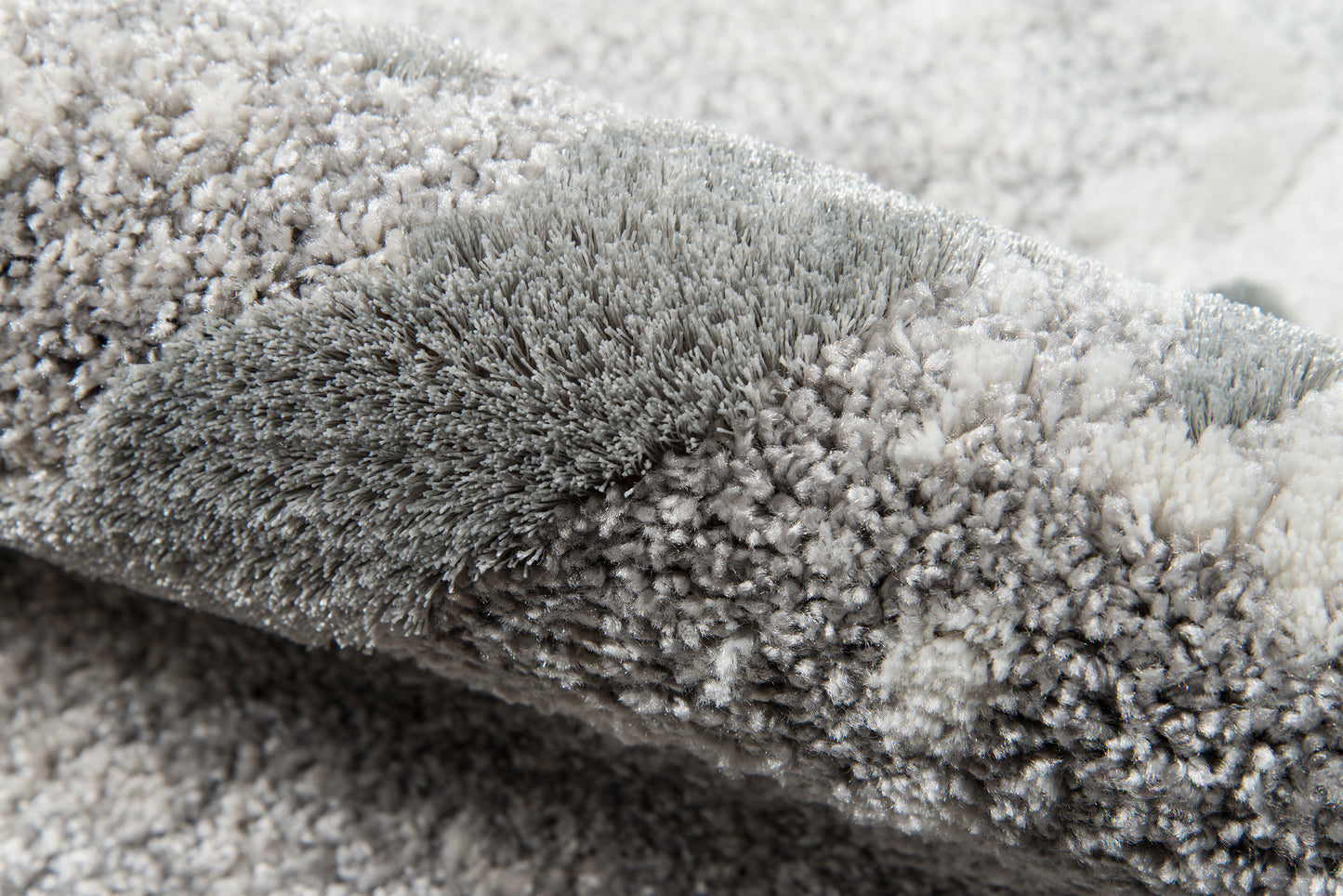 Close-up of a gray shag rug with dense plush pile & soft microfiber fibers.