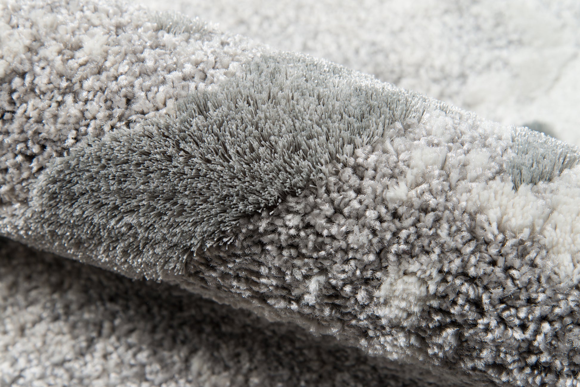 Close-up of a gray shag rug with dense plush pile & soft microfiber fibers.