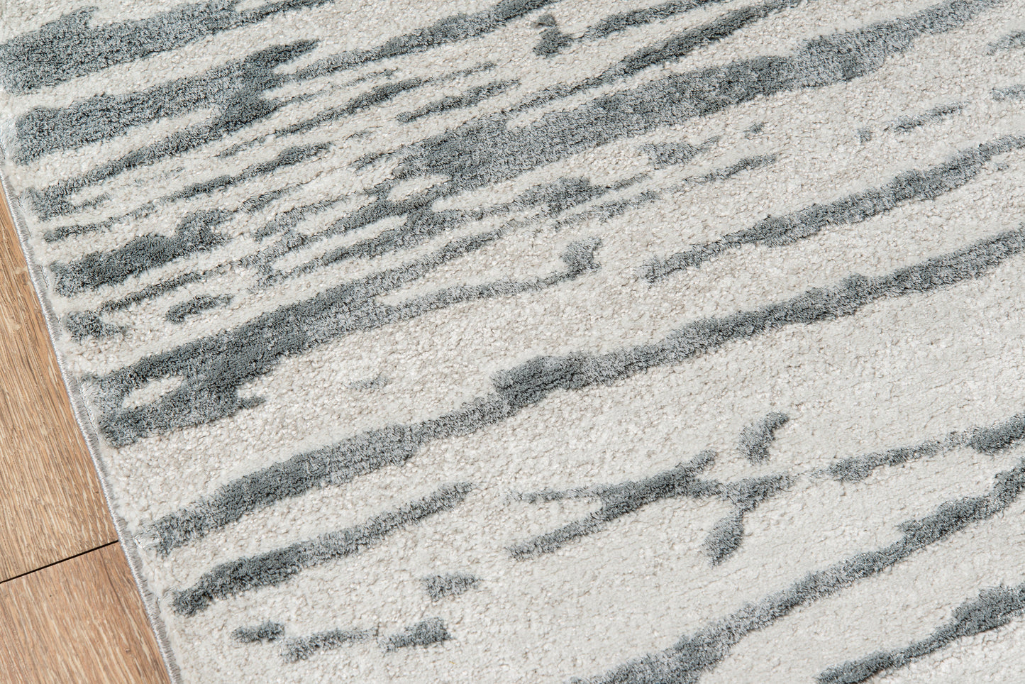 Gray abstract striped area rug with cream background on hardwood floor, modern geometric design.