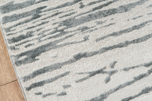 Gray abstract striped area rug with cream background on hardwood floor, modern geometric design.