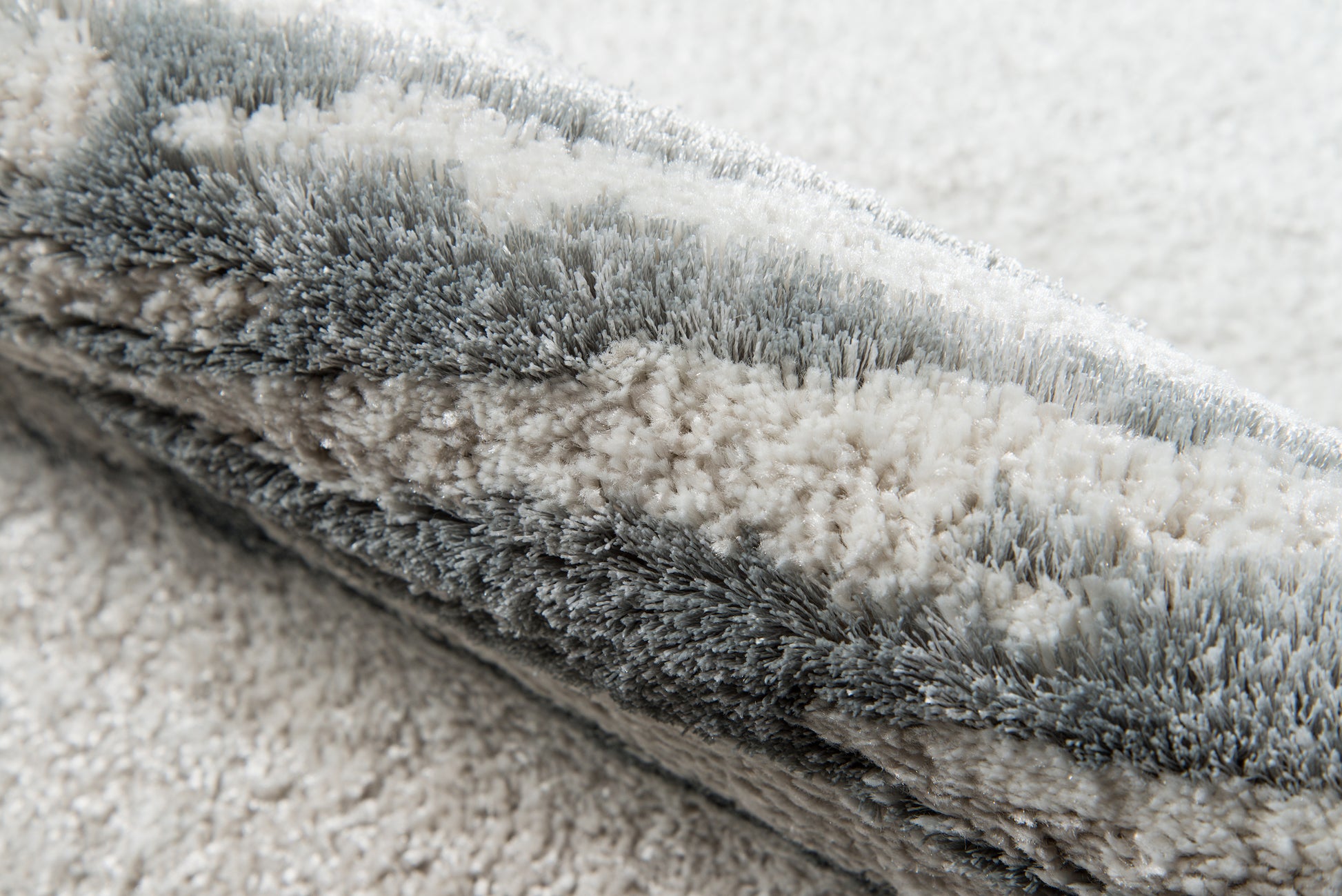 Soft grey shag rug with dense, fluffy fibers in layered gray tones & plush, modern throw rug.