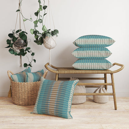 Turquoise striped cushions in teal & blue on a curved rattan bench; wicker basket of extra pillows and hanging planters.