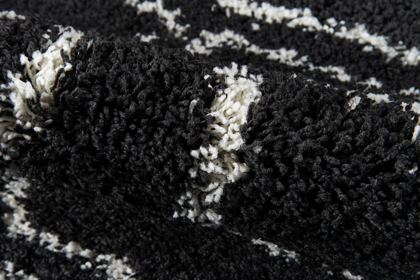 Close-up of black & white shag rug with high-pile, chunky fibers & abstract pattern.