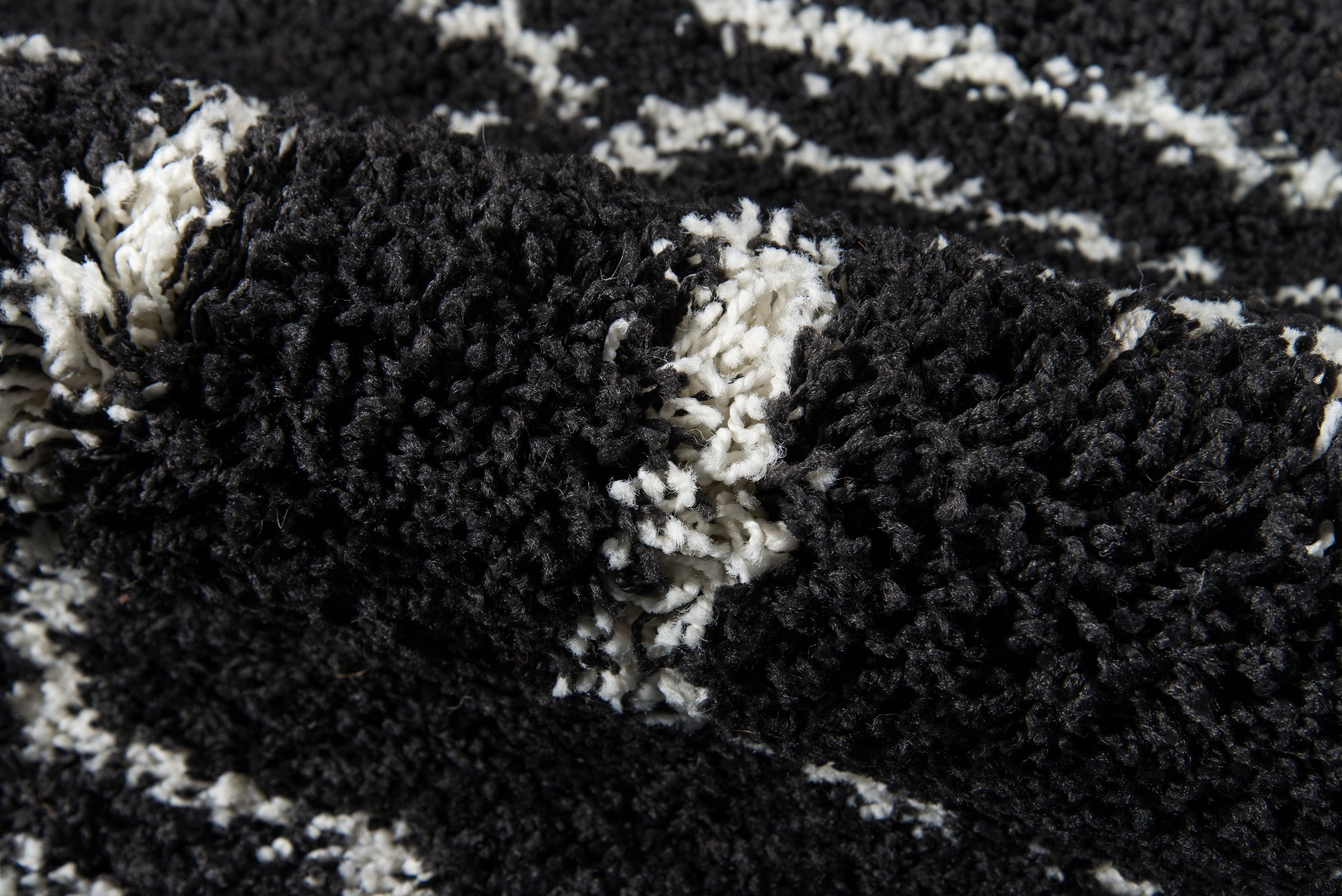 Close-up of black & white shag rug with high-pile, chunky fibers & abstract pattern.