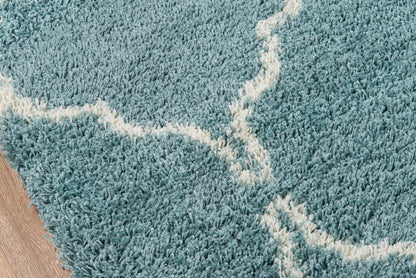 Teal plush shag rug with cream curved lines on a wooden floor.