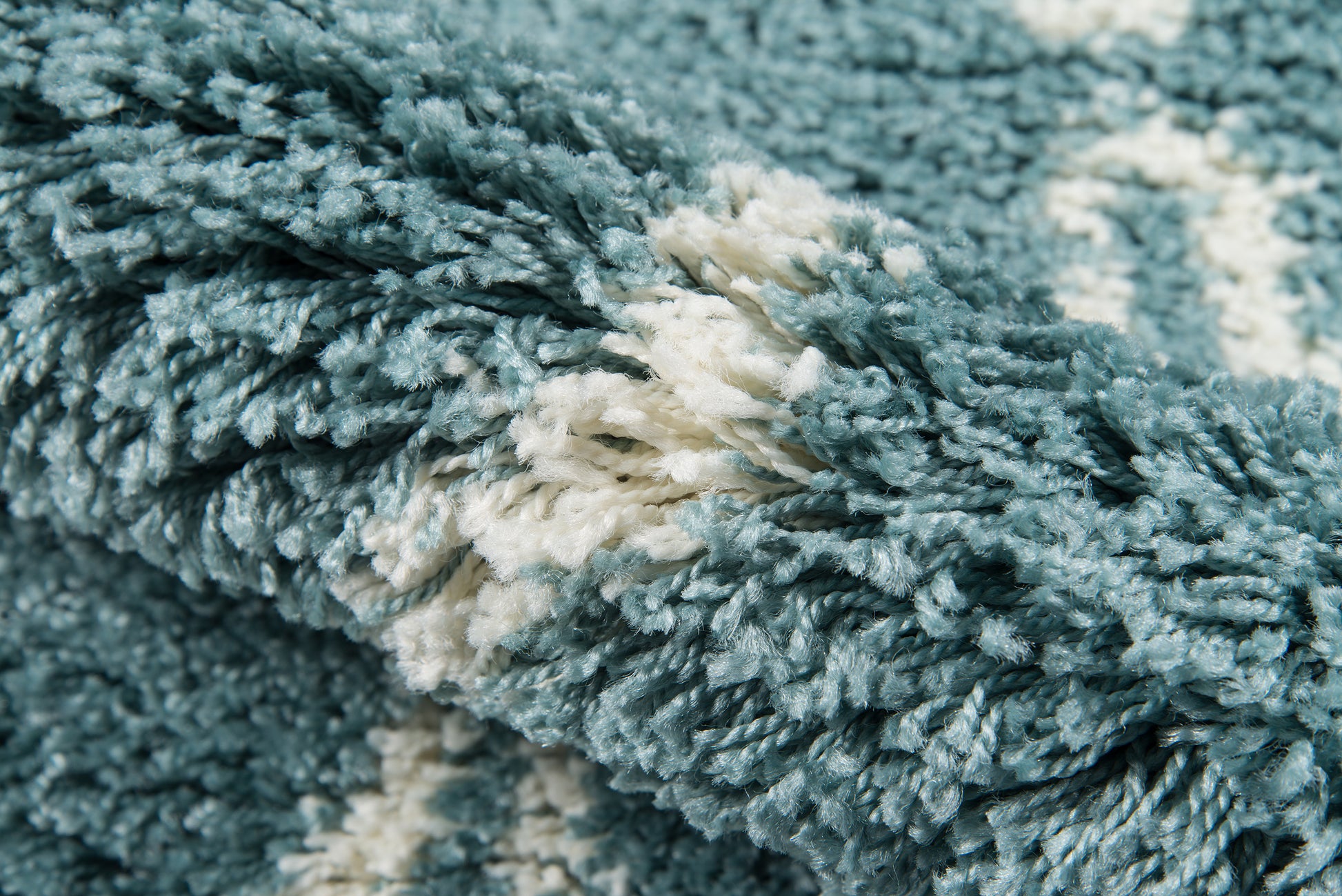 Close-up of a blue-teal shag rug with fluffy pile and cream accents.