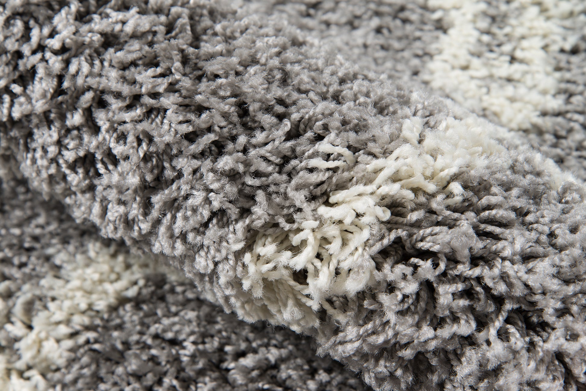 Close-up of a gray and white shag rug with thick, plush, twisted fibers.