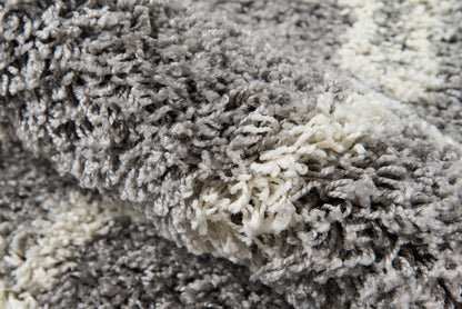 Close-up of a gray and white shag rug with thick, plush, twisted fibers.