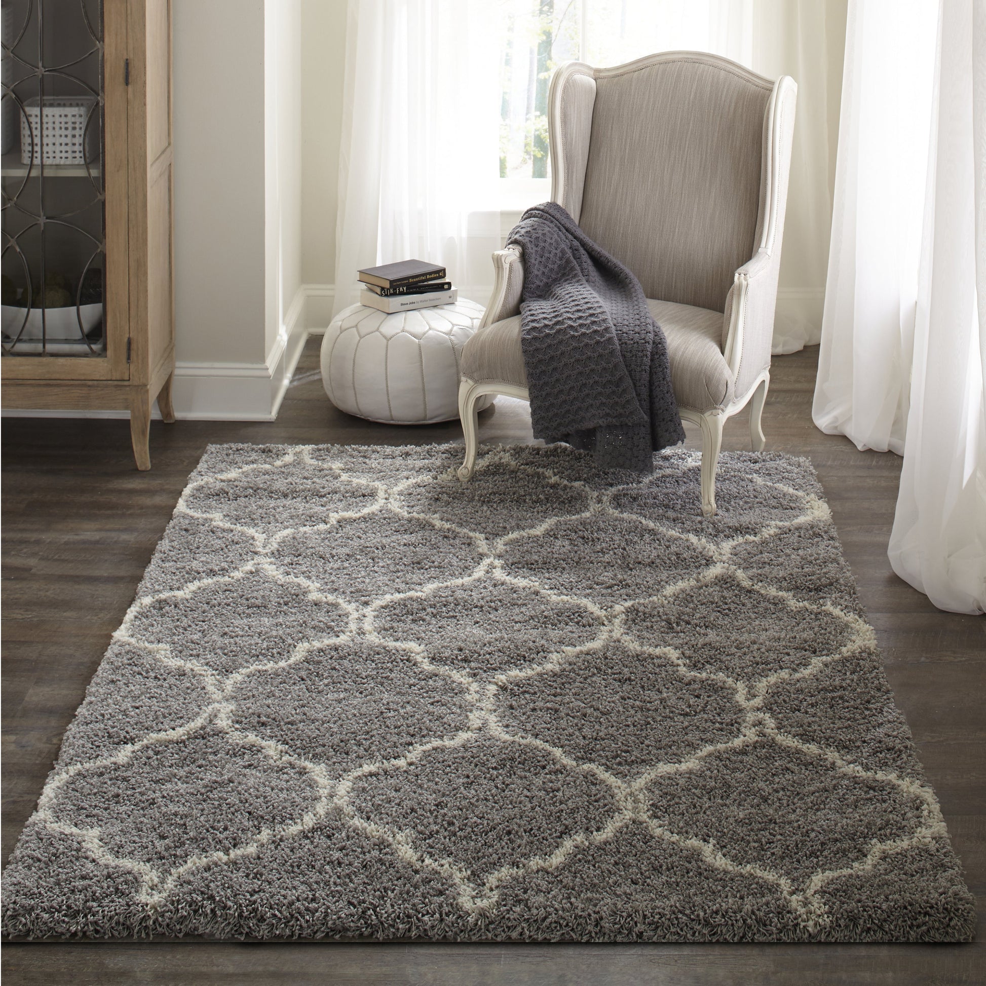 Soft gray shag rug with cream lattice pattern; neutral living room with a beige tufted armchair and dark gray throw
