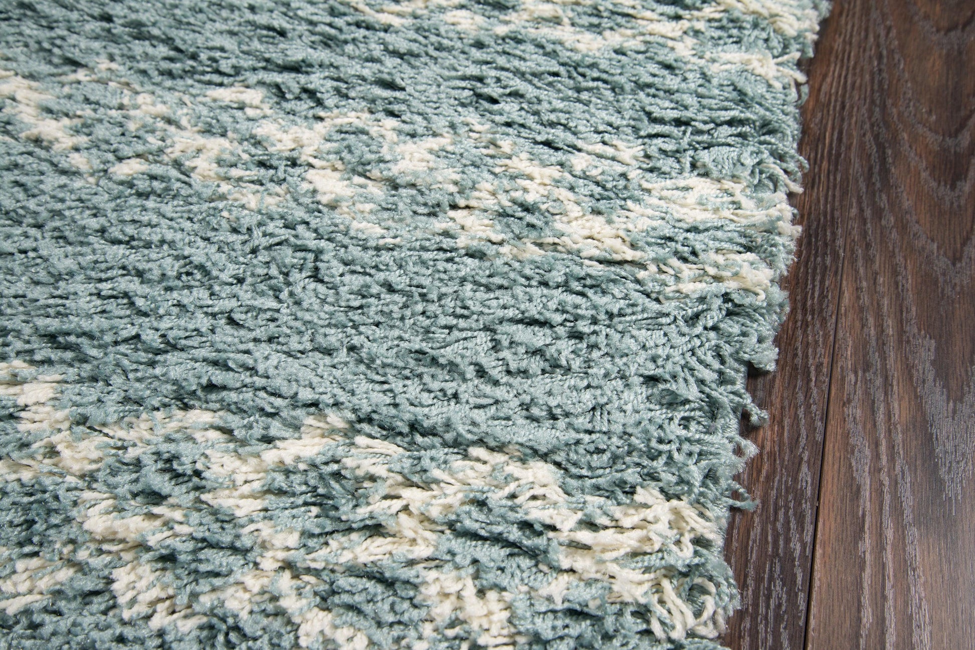 Teal shag rug with cream stripes on dark wood floor; plush texture, modern cozy living room style.